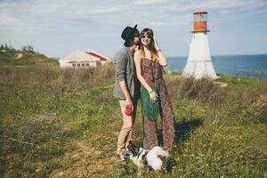 encantador sonriente joven elegante hipster Pareja en amor caminando con perro en campo foto