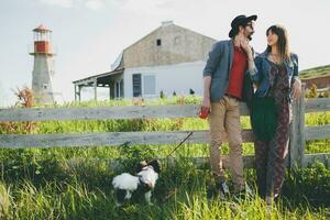 stylish hipster couple in love walking with dog in countryside photo