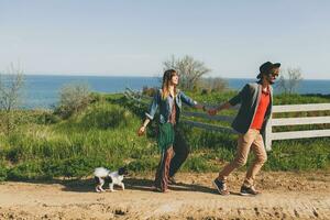 stylish hipster couple in love walking with dog in countryside photo