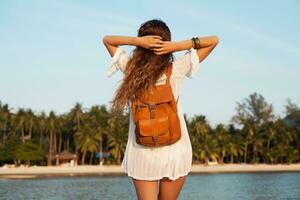 slim beautiful woman in white cotton dress walking on tropical beach photo