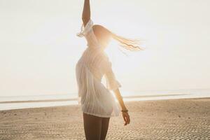 Delgado hermosa mujer en blanco algodón vestir caminando en tropical playa foto