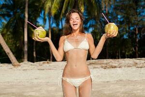young skinny woman in white bikini swimwear holding coconuts photo