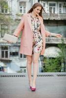 cute young beautiful stylish woman walking in street in pink coat photo