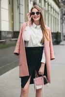 young stylish beautiful woman walking in street, wearing pink coat photo