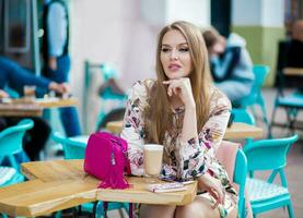 sexy young hipster stylish woman sitting in cafe, spring summer fashion trend, drinking coffee photo