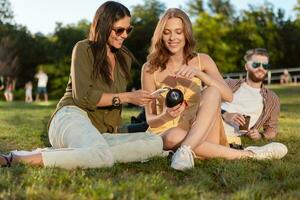 company of friends having fun together in park listening to music photo