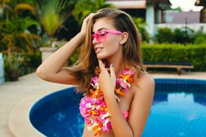 sexy woman on summer vacation having fun at pool wearing bikini and pink sunglasses photo