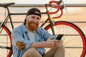 handsome bearded man traveling with bicycle in morning sunrise by the sea photo