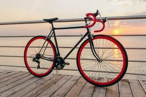 hipster bicicleta a puesta de sol mar foto