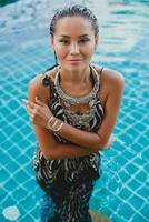 young asian sexy beautiful woman in tropical dress, zebra print, posing in pool photo