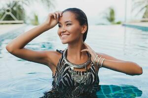 young asian sexy beautiful woman in tropical dress, zebra print, posing in pool photo