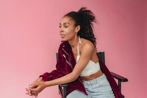 attractive black african american woman in stylish outfit on pink background photo