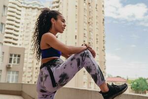 attractive black african american woman in sport fitness outfit on rooftop making work out photo