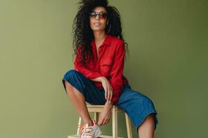 attractive black african american woman in stylish outfit on green studio background photo
