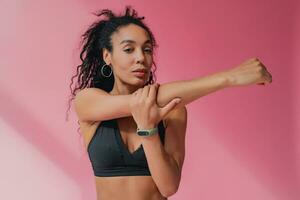 attractive black african american woman in black leggins fitness outfit on pink background photo