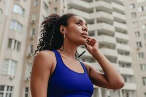 attractive black african american woman in sport fitness outfit on rooftop making work out photo