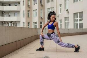 attractive black african american woman in sport fitness outfit on rooftop making work out photo