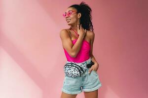 attractive black african american woman in stylish outfit on pink background photo