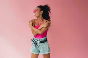 attractive black african american woman in stylish outfit on pink background photo