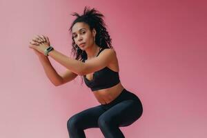 attractive black african american woman in black leggins fitness outfit on pink background photo