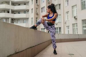 attractive black african american woman in sport fitness outfit on rooftop making work out photo