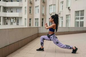 attractive black african american woman in sport fitness outfit on rooftop making work out photo