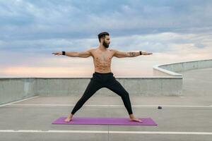 atractivo hansome hombre con atlético fuerte cuerpo haciendo Mañana yoga asana al aire libre foto