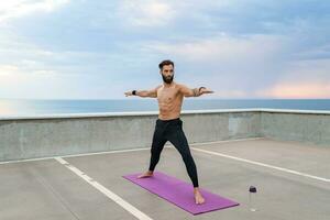 attractive hansome man with athletic strong body doing morning yoga asana outdoors photo