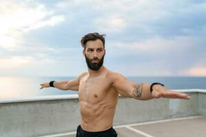 atractivo hansome hombre con atlético fuerte cuerpo haciendo Mañana yoga asana al aire libre foto