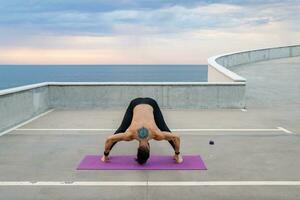 attractive hansome man with athletic strong body doing morning yoga asana outdoors photo