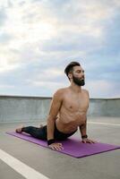 attractive hansome man with athletic strong body doing morning yoga asana outdoors photo