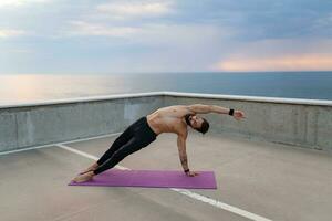 attractive hansome man with athletic strong body doing morning yoga asana outdoors photo