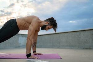 attractive hansome man with athletic strong body doing morning yoga asana outdoors photo