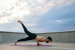 atractivo hansome hombre con atlético fuerte cuerpo haciendo Mañana yoga asana al aire libre foto