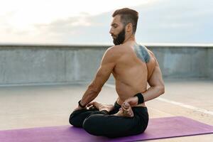 atractivo hansome hombre con atlético fuerte cuerpo haciendo Mañana yoga asana al aire libre foto