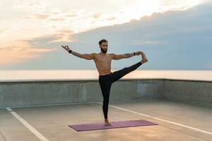 atractivo hansome hombre con atlético fuerte cuerpo haciendo Mañana yoga asana al aire libre foto