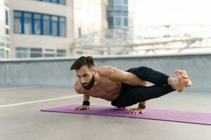 atractivo hansome hombre con atlético fuerte cuerpo haciendo Mañana yoga asana al aire libre foto