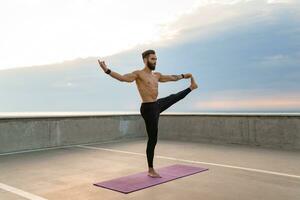 atractivo hansome hombre con atlético fuerte cuerpo haciendo Mañana yoga asana al aire libre foto