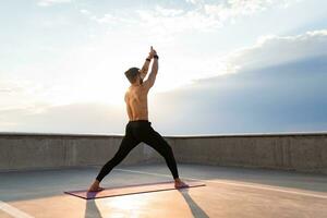 atractivo hansome hombre con atlético fuerte cuerpo haciendo Mañana yoga asana al aire libre foto