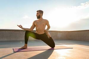 atractivo hansome hombre con atlético fuerte cuerpo haciendo Mañana yoga asana al aire libre foto