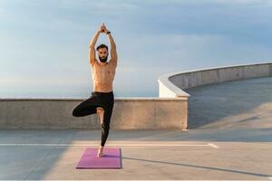 attractive hansome man with athletic strong body doing morning yoga asana outdoors photo