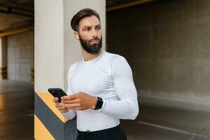 athletic strong hansome man on morning fitness workout exercise in sportswear using smartphone photo