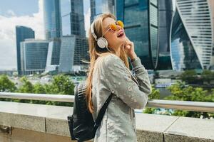 young hipster woman having fun in street listening to music on headphones photo