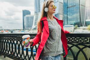 young hipster woman having fun in street listening to music on headphones photo