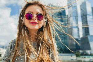 young hipster woman having fun in street listening to music on headphones photo