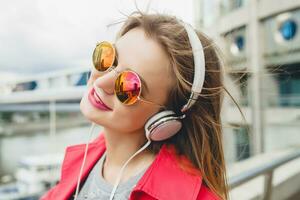 young hipster woman having fun in street listening to music on headphones photo