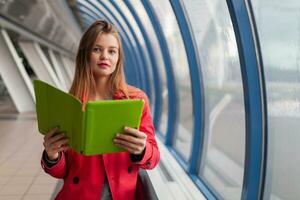 young pretty woman in casual outfit holding tablet laptop in urban building photo