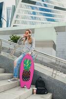 young hipster woman in street with balance board wearing sweater and jeans photo