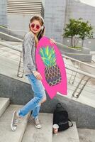 young hipster woman in street with balance board wearing sweater and jeans photo