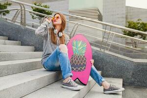 young hipster woman in street with balance board wearing sweater and jeans photo